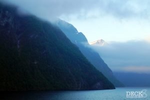 Der Geirangerfjord vom Schiff aus, morgens mit Wolken über dem Fjord und etwas Sonne über den Berggipeln